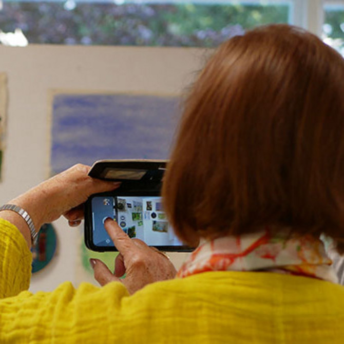 Eine Frau fotografiert in einer Ausstellung mit ihrem Handy