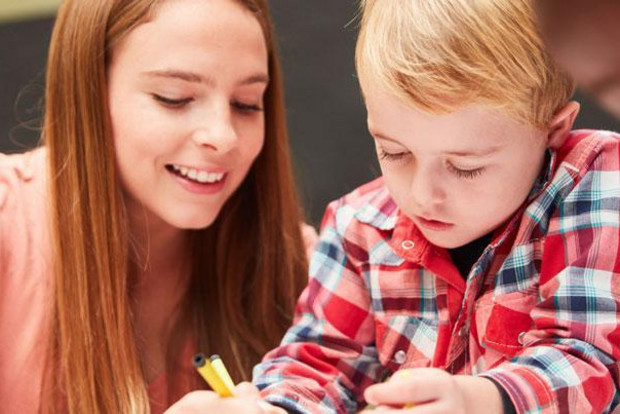 Eine junge Frau malt mit einem kleinen Jungen