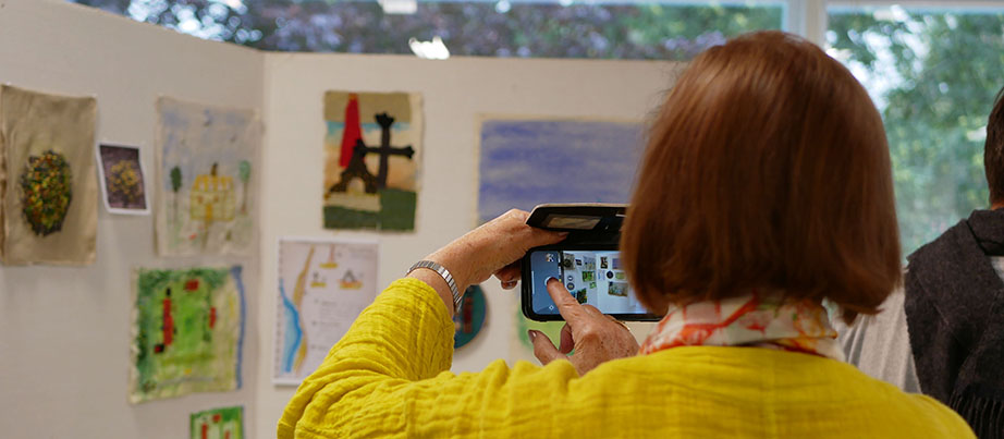 Eine Frau fotografiert mit dem Handy in einer Ausstellung